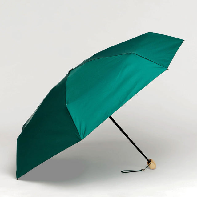 Green umbrella with a wooden handle on a plain background