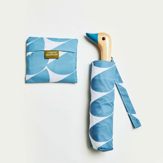 Foldable umbrella with blue and white pattern and matching carrying case on a light gray background