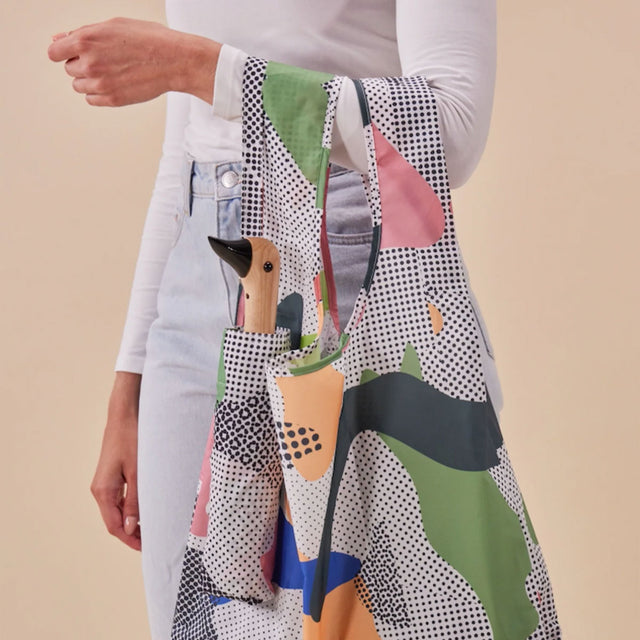 Person holding a colorful patterned bag with a neutral background