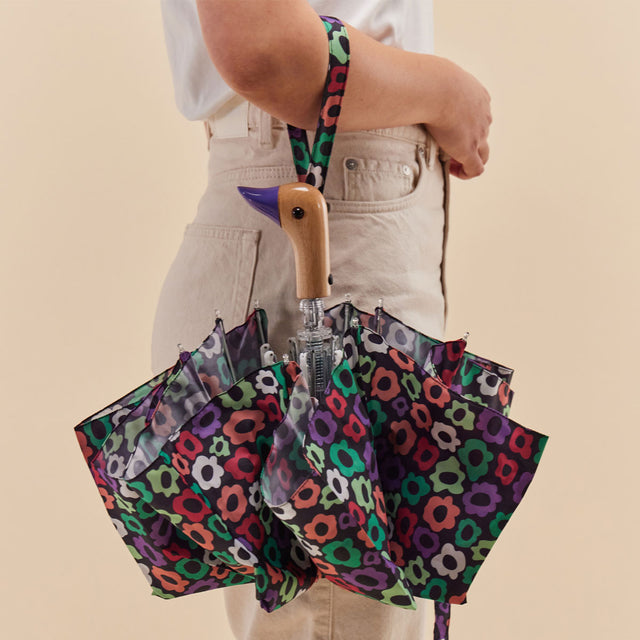 Person holding a colorful floral-patterned umbrella with a plain background