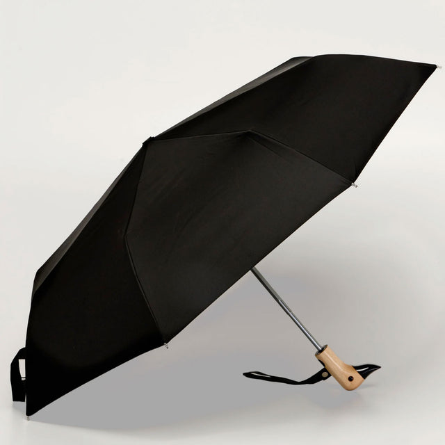 Black compact umbrella with carved duck-head handle, open from a side angle