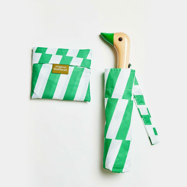 Green and white striped umbrella with duckhead wooden handle on a light gray background