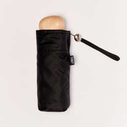 Black mini umbrella with wooden handle on a light background