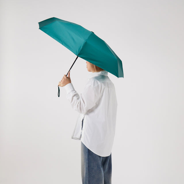 Person holding a teal umbrella against a white background