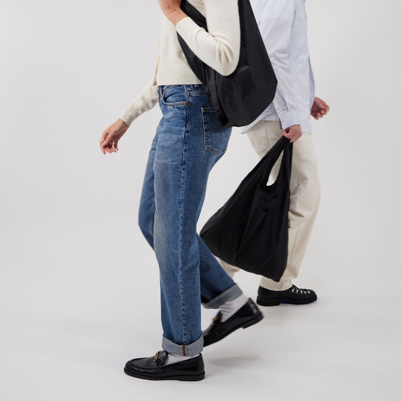 Model shot of two people carrying a black reusable tote bag