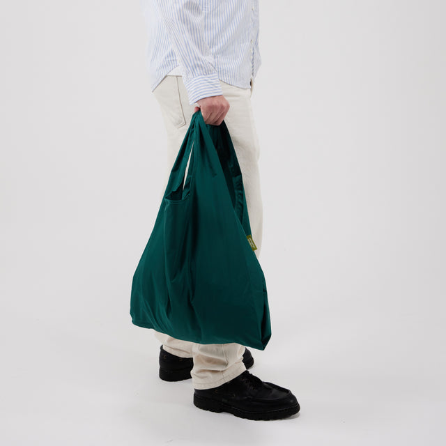 Person holding a green bag against a white background