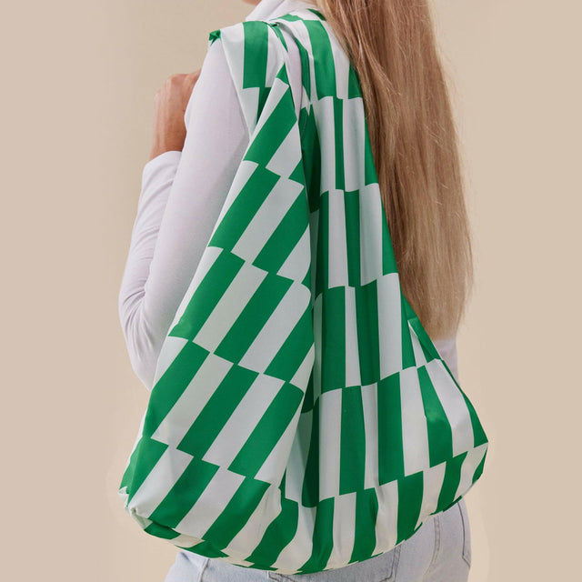 green and white striped reusable tote bag being held over a shoulder