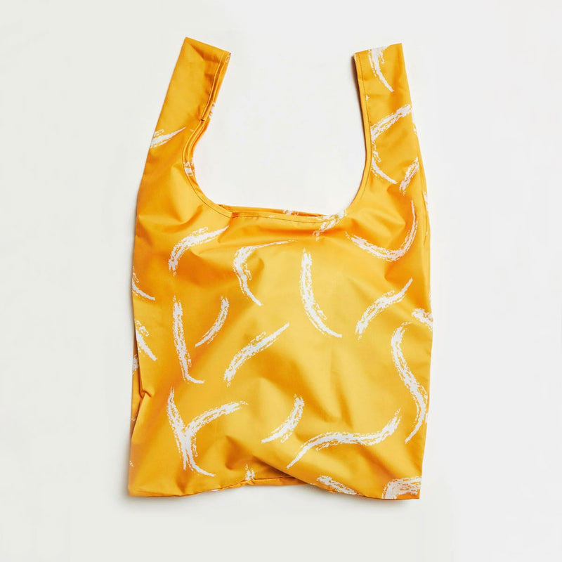 Yellow reusable bag with white brush strokes on a light gray background