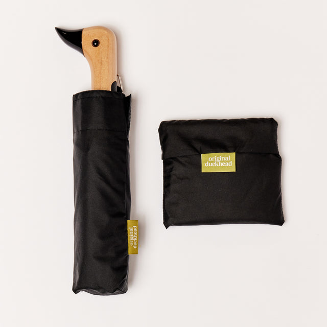 Black Reusable Bag in Pouch with a closed black umbrella with duckhead carved handle